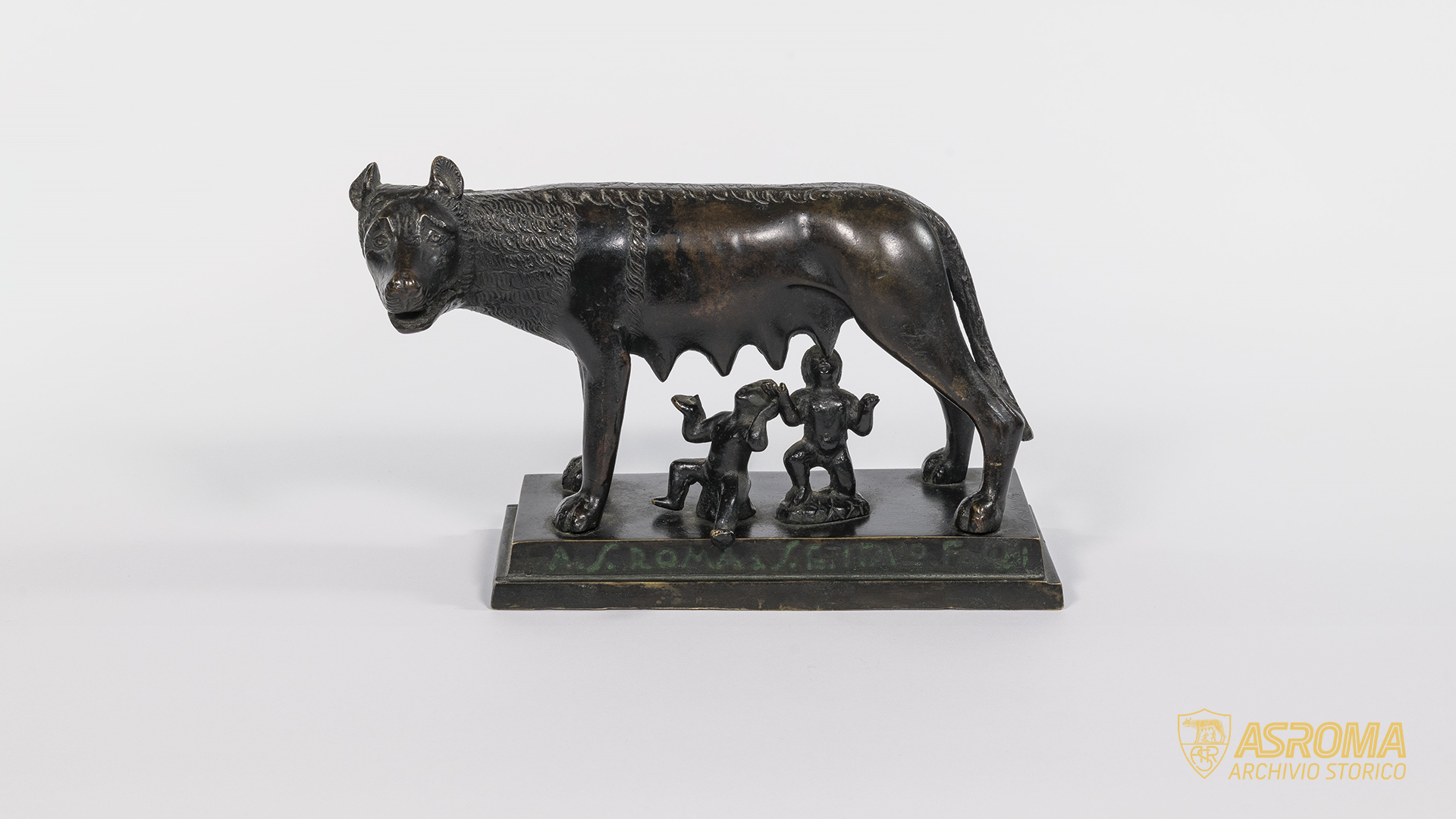 Riproduzione in bronzo della Lupa Capitolina donata dall'Associazione Sportiva Roma a Italo Foschi. Sul profilo anteriore del basamento, realizzato anch'esso in bronzo, è presente una dedica in rilievo divenuta verde per ossidazione: "A.S. Roma a S.E. Italo Foschi" 
(Archivio Storico AS Roma / Fondo Italo Foschi-Famiglia Zingarelli)